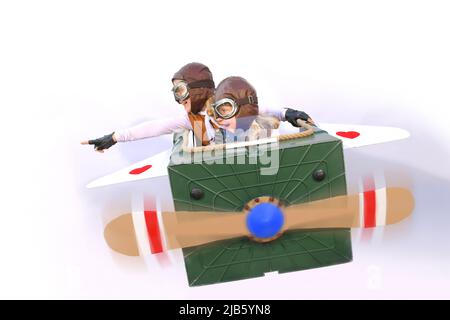 Twin sisters sit at the controls of their imaginative airplane.  They play pilot and co-pilot with an airplane made  from items found in their garden. Stock Photo