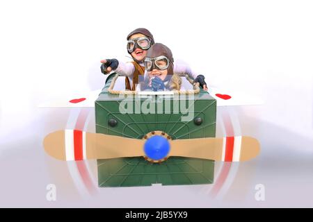 Twin sisters sit at the controls of their imaginative airplane.  They play pilot and co-pilot with an airplane made  from items found in their garden. Stock Photo