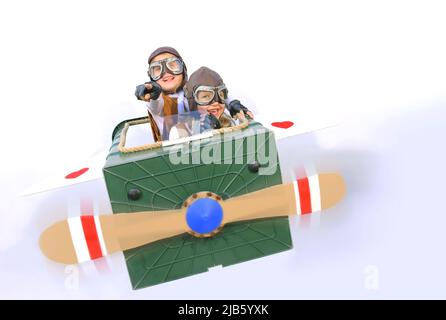 Twin sisters sit at the controls of their imaginative airplane.  They play pilot and co-pilot with an airplane made  from items found in their garden. Stock Photo