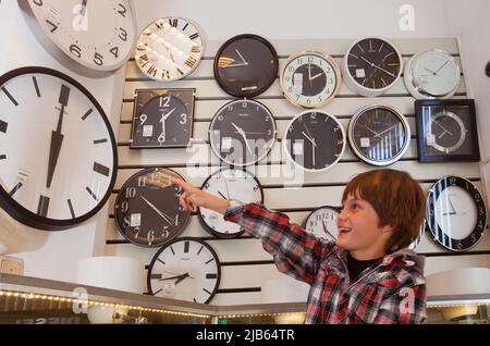 Netherlands, Velp. Boy points at the time in a shop full with clocks. Stock Photo
