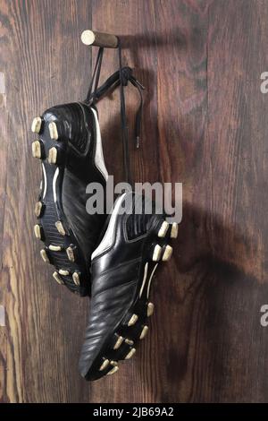 A pair of soccer boots hanging on a wooden wall. The end of the football career Stock Photo