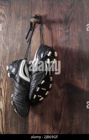 A pair of soccer boots hanging on a wooden wall. The end of the football career Stock Photo