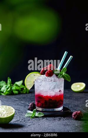 Cocktail with Rum or Vodka, Soda, Raspberry and Blackberry Puree, Lime and Mint in the Glass on the Dark Grey Background Stock Photo