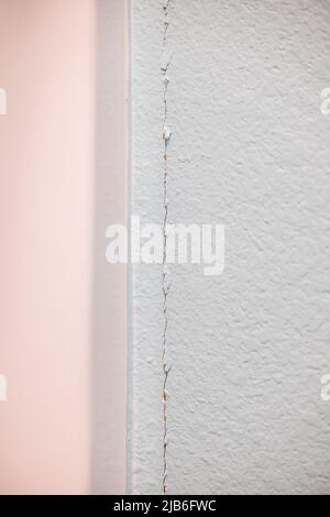 A crack in the greige wall where the sheetrock meets at the corner in a new construction house needing repairs Stock Photo