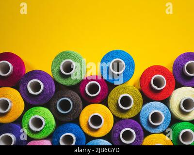 Multicolored threads for sewing and embroidery on the yellow background Stock Photo