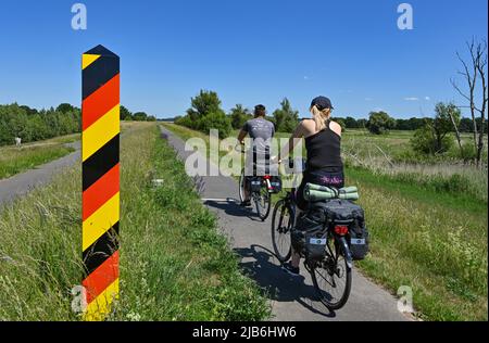 03 June 2022, Brandenburg, Reitwein: Cyclists are on the Oder-Neisse Cycle Path, which is located in the Oderbruch on the dike on the German-Polish border river Oder. The Oder-Neisse Cycle Path is a long-distance cycle path in the Czech Republic and Germany that is about 630 kilometers long. It largely follows Germany's eastern border with Poland. The Oder-Neisse Cycle Route runs in a south-north direction for about 55 kilometers through the Czech Republic, starting at the source of the Neisse River and following it to where the Neisse flows into the Oder. Westward of the Oder, the trail then Stock Photo