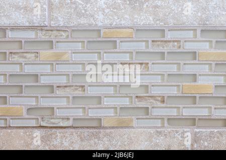 Clear colored glass and metallic small accent strip tiles in a master bathroom with beige tiled walls Stock Photo
