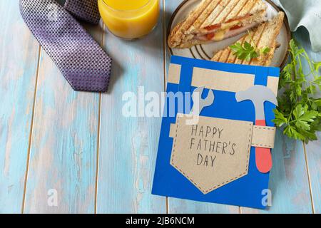 Celebrating Father's Day. Breakfast. Father’s Day card and home DIY sandwich with bacon on wooden table. Copy space. Stock Photo