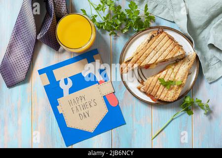 Celebrating Father's Day. Breakfast. Father’s Day card and home DIY sandwich with bacon on wooden table. View from above. Stock Photo