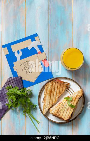 Celebrating Father's Day. Breakfast. Father’s Day card and home DIY sandwich with bacon on wooden table. View from above. Copy space. Stock Photo