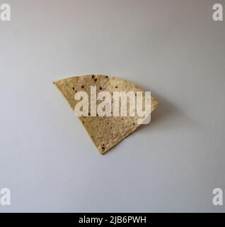 A Single Yellow Corn Tortilla Chip on a White Background Stock Photo