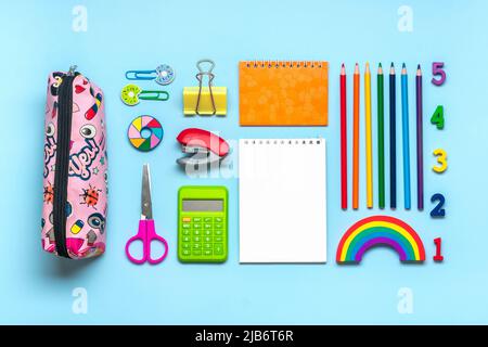 Frame from school and office supplies Paper clips, pens, calculator, sharpener, notepad, stapler isolated on blue background Flat lay Top view Back to Stock Photo