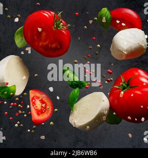 Falling caprese salad ingredients on dark background. Italian appetizer Stock Photo