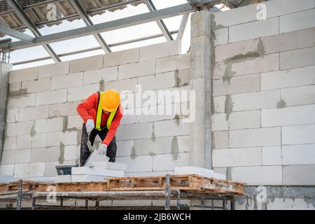 A Construction worker are using adhesive mortar for lightweight brickwork at the construction site. Stock Photo