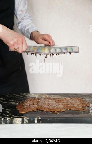 chocolatier pouring caramel filling into chocolate mold preparing handmade  candy Stock Photo - Alamy