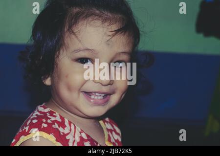 Portrait Of Adorable Cute Indian happy funny baby with dimples age one year six months smiling and Posing looking at camera. Happy Childhood And Child Stock Photo