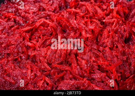 Chopped beetroot in a pan as well as spices and herbs on a wooden cutting board as ingredients in the preparation of traditional Ukrainian borscht Stock Photo