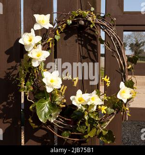 A spring flower outdoor wreath hanging on a wooden gate Stock Photo