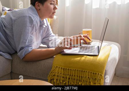Woman with credit card using laptop during shopping online. E-shopping from home during Black Friday and Cyber Monday sales Stock Photo