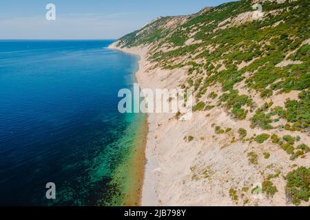 Coastline with quiet sea and highest cliff on coastline. Summer day on blue sea. Aerial view Stock Photo