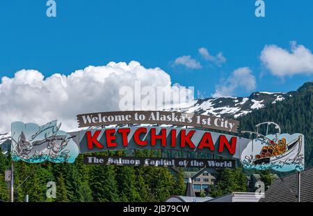 Ketchikan, Alaska, USA - July 17, 2011: Large free standing colorful Welcome sign to the Salmon Capital of the World under blue cloudscape and snow co Stock Photo