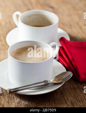 Two cups of espresso coffee on a wood tabletop with red napkin Stock Photo
