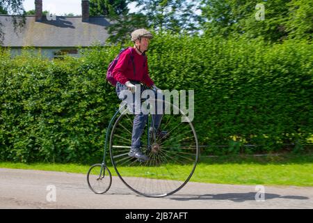 Man riding Victorian penny farthing, high wheel, high wheeler or ordinary bicycle at Worden Park Chorley June Festival, 2022 Stock Photo