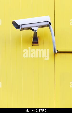 CCTV camera on the exterior textured wall in yellow color Stock Photo
