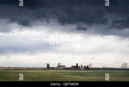 A hail storm forms above a country homestead on the Canadian prairies during an extreme weather event in Rocky View County Alberta Canada.