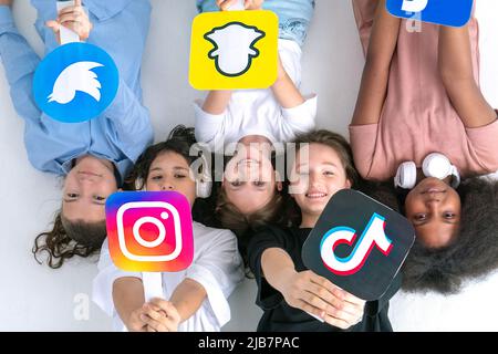 Multiracial teenagers friends hands hold social media icons in their hands. Teenagers addicted to new technology trends - concept of youth, technology Stock Photo