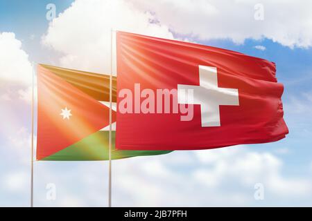 Sunny blue sky and flags of switzerland and jordan Stock Photo