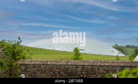 Futuristic conservatory dome of glass panels in steel joists, set into a hillside. Wales Botanic Garden world's largest single span glasshouse Stock Photo