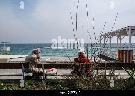 Elderly women seen sitting on a bench by the beach. The third largest city in Ukraine located in the south of the country, Odessa is the main naval base of the Ukrainian Navy and the administrative center of the Odessa region. The city, standing on the shore of the Odessa Gulf of the Black Sea, is the largest commercial sea port of Ukraine. Stock Photo