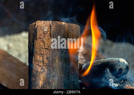 Mesquite dried-wood log emits a massive orange flame inside a large fire pit. Stock Photo