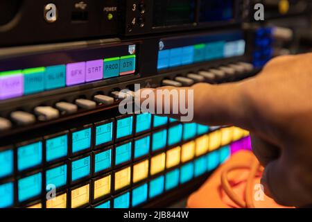 Person using an intercom panel to communicate during a live broadcast television production, shallow focus. Stock Photo