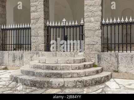 Circular steps leading up to a gate in black and white wrought iron fence Stock Photo