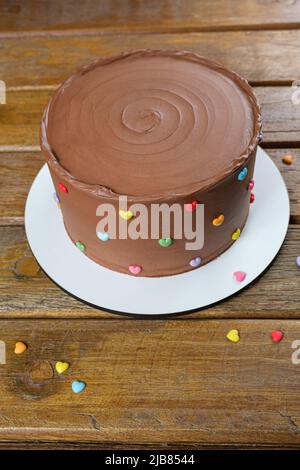 Chocolate cake with semisweet chocolate ganache frosting. On the wooden table vertical. Stock Photo