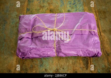 gift wrapped present, wrapped in purple tissue and with a string bow Stock Photo
