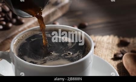 Pouring freshly brewed hot cezve coffee into a white cup, close up. Stock Photo