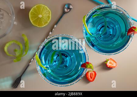 Fresh homemade blue margarita cocktail garnished with lime zest and strawberries Stock Photo