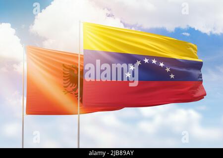 Venezuela and Albania flags waving together in the wind on blue cloudy ...