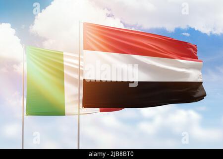 Yemen and Italy flags waving together in the wind on blue cloudy sky ...