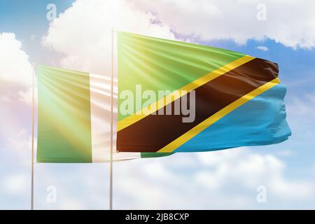 Tanzania and Nigeria flags waving together in the wind on blue cloudy ...