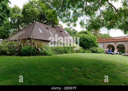 London, Greater London, England, May 28 2022: Family relaxing on the lawn by the cottage at Holland Park in the Kensington area in the spring. Stock Photo