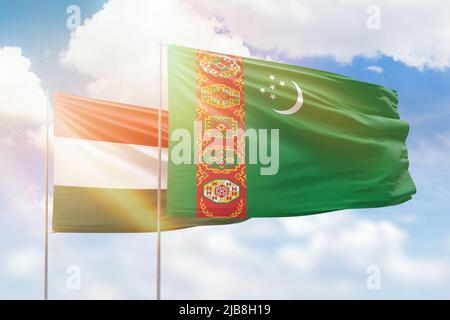 Turkmenistan and Hungary flags waving together in the wind on blue ...