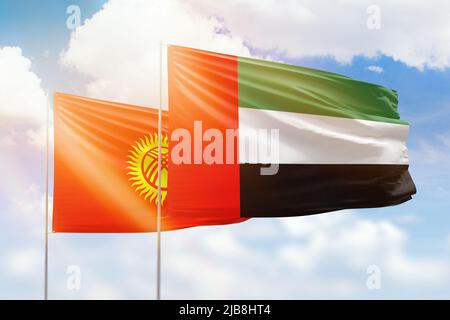 Sunny blue sky and flags of united arab emirates and kyrgyzstan Stock Photo