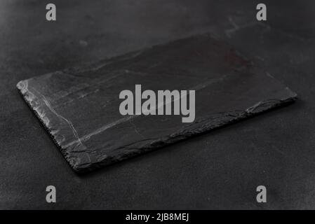 rectangular black cheese board on a dark background Stock Photo