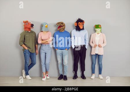 Group of people wearing funny strange absurd animal masks standing by office wall Stock Photo