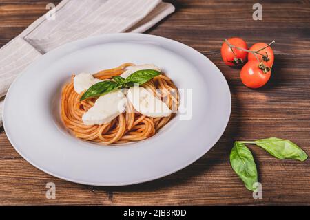 Plate of spaghetti topped with tomato, mozzarella and basil, to recreate the colors of the Italian flag Stock Photo