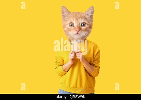 Cute cat with human body holding smartphone on yellow background Stock Photo